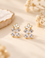 Gold-tone floral stud earrings with white enamel flowers and sparkling clear crystal petals .