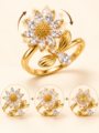 Gold floral ring with sparkling clear stones and elegant leaf detailing on a warm ivory background, Baarah Jewels.
