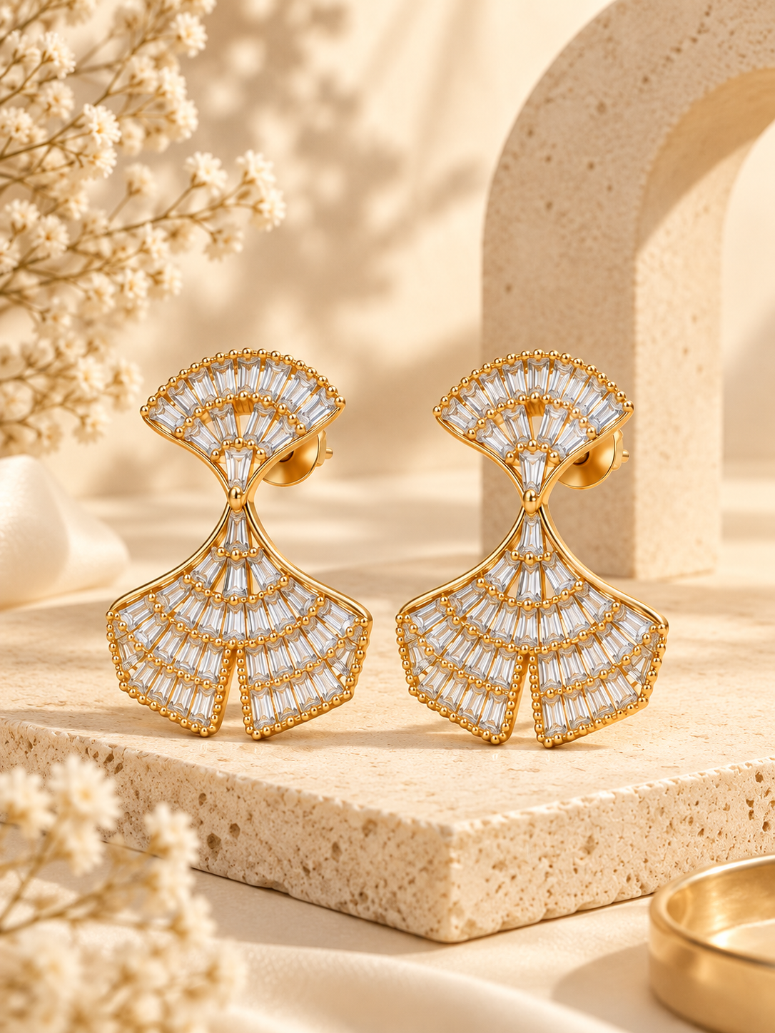 Gold-tone fan-shaped hanging earrings with sparkling clear baguette-cut stones and intricate detailing.