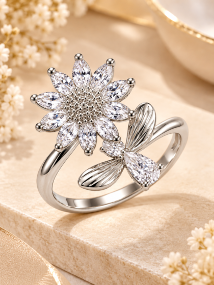 Rhodium-finish floral ring featuring sparkling clear marquise-cut stones, a delicate leaf design, and a polished silver-tone band on a warm ivory background.