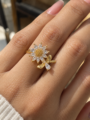 Gold floral ring with sparkling clear stones and elegant leaf detailing on a warm ivory background, Baarah Jewels.